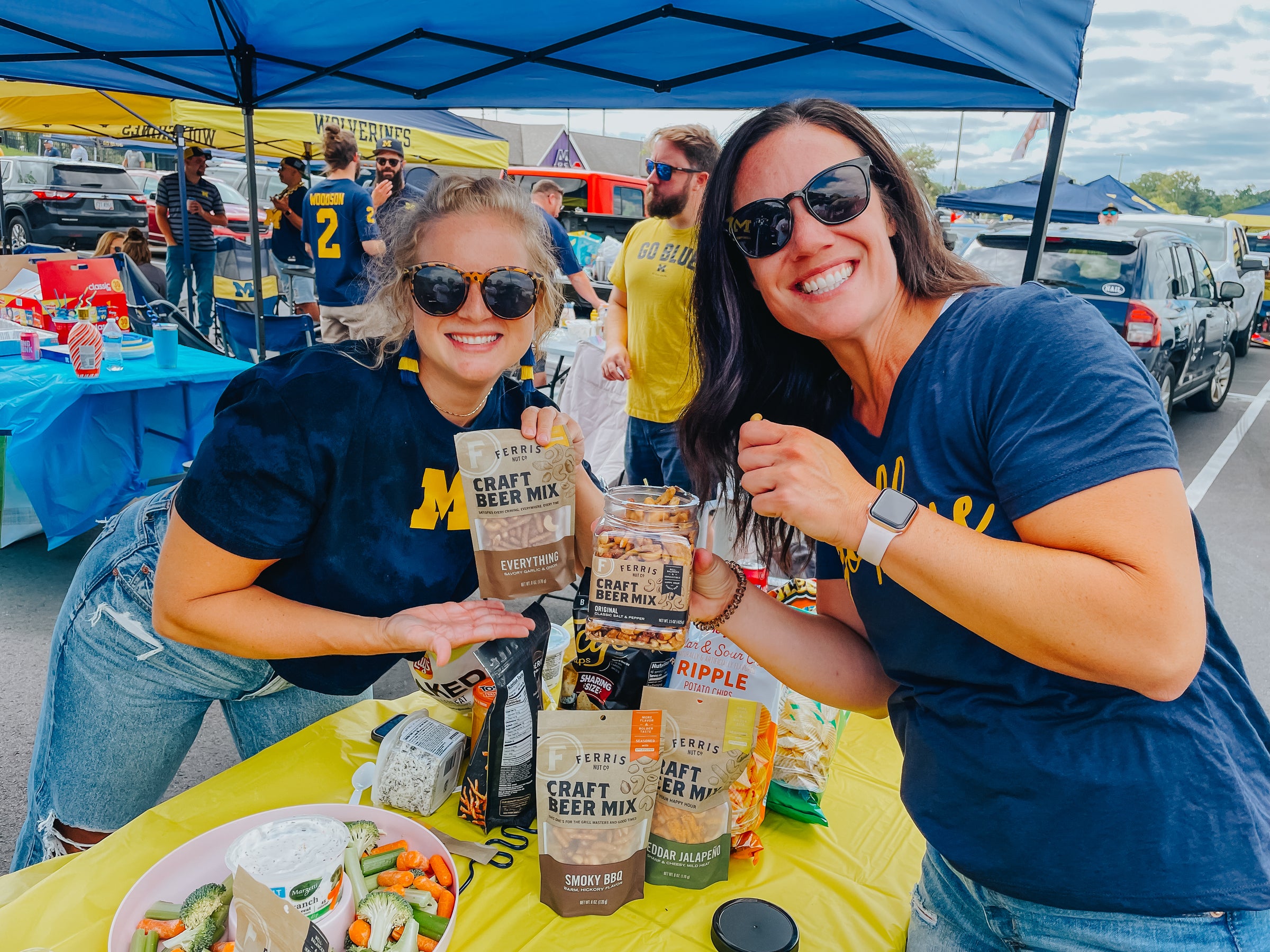 Two women at a outdoor event holding bags of Michigan-themed snacks.